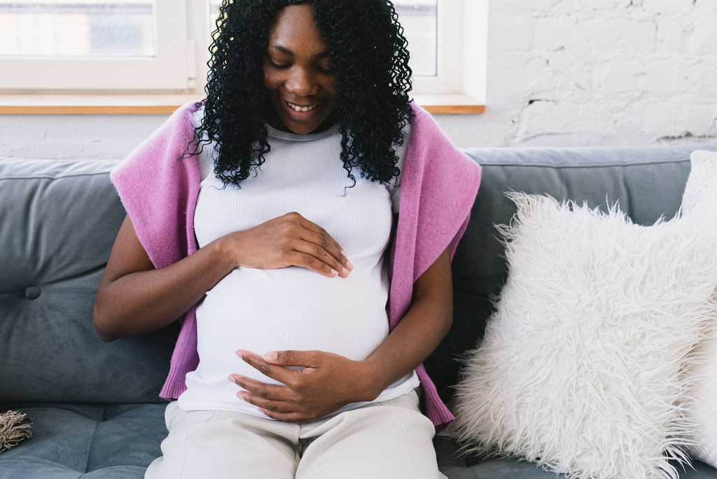 how to prepare for labor - woman sits on couch cradling pregnancy bump
