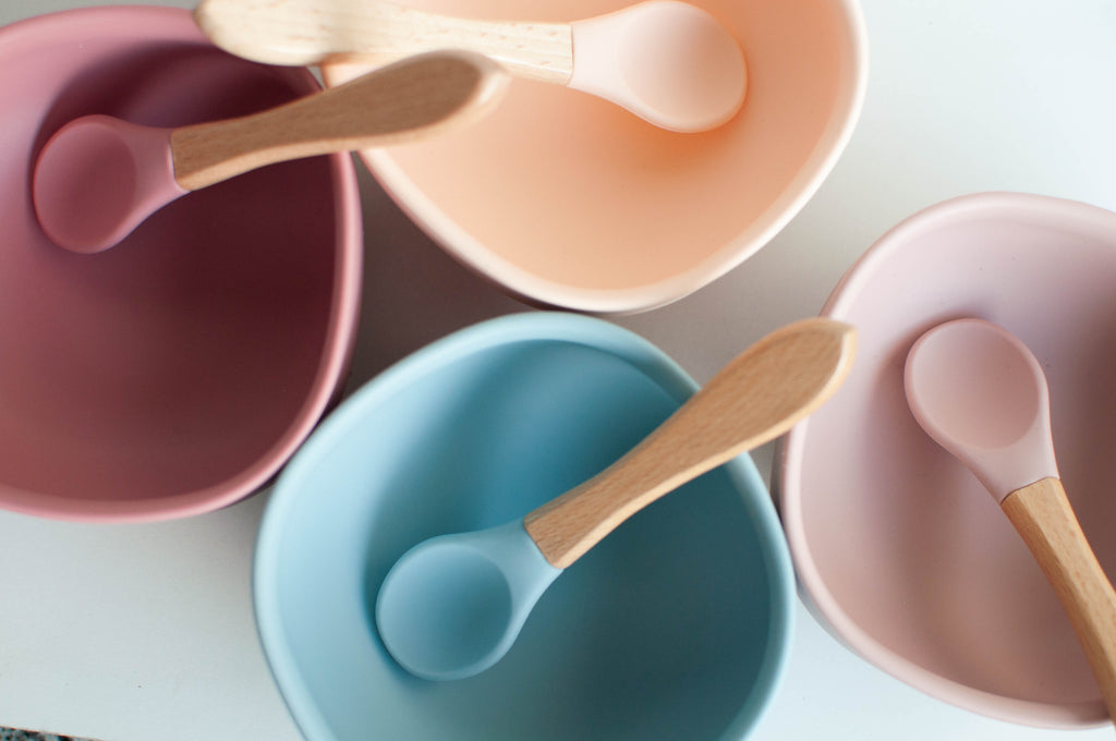 four colorful bowls and spoons for baby weaning